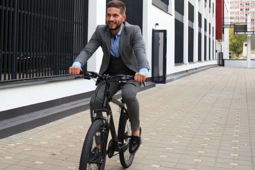 A male office worker is cycling outside the office building