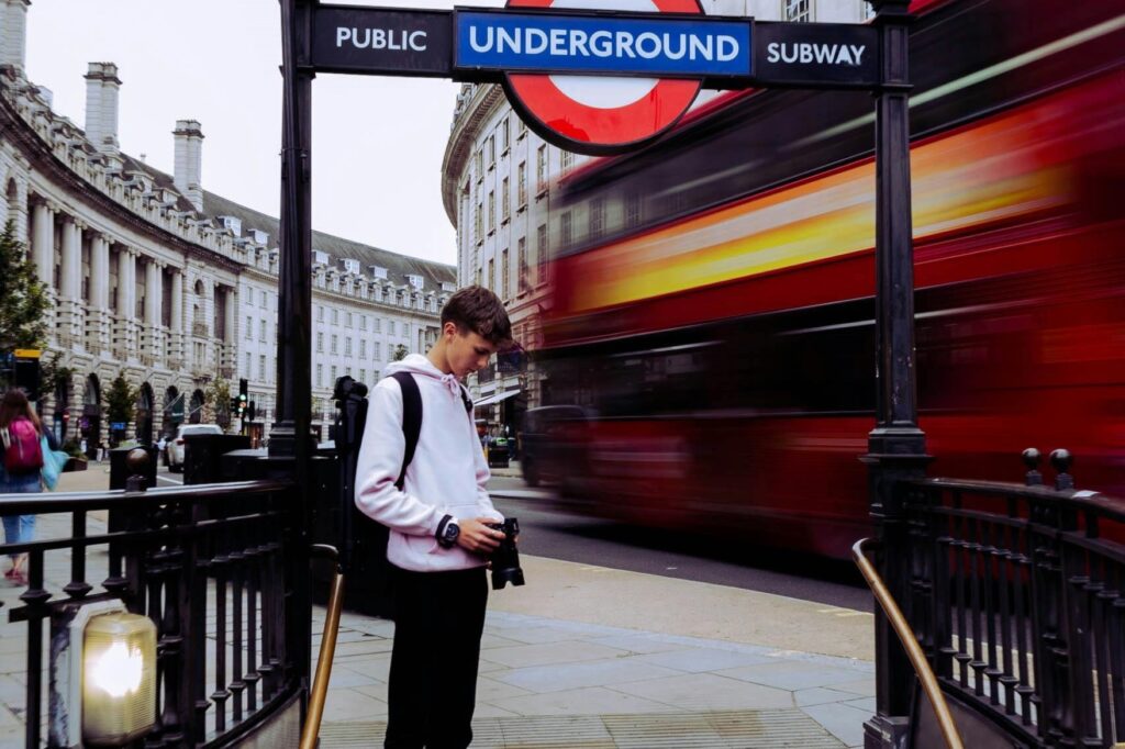 A subway station sign and the red bus in the background