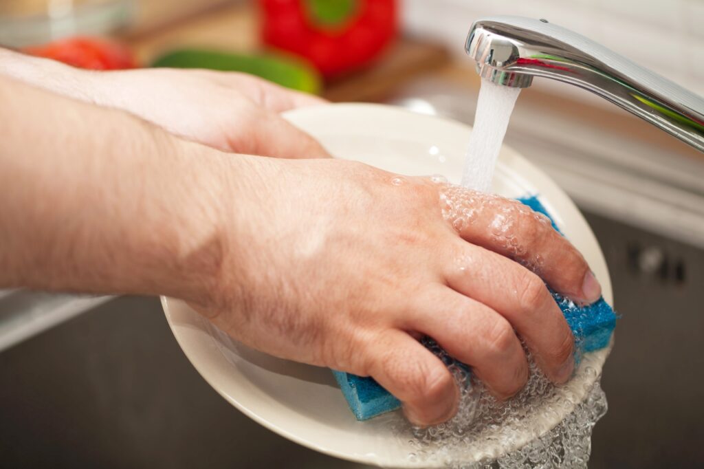 Cropped image of a man's hands washing dishes