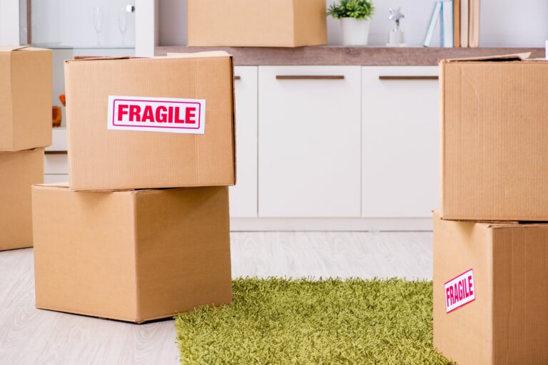 Moving boxes on the floor some with 'Fragile' label in the concept of 'What Are the Benefits of Hiring Professional Packers for Your Move to Leyton'.